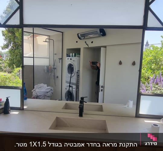 מראה גדולה עם כיור ומוצרי טיפוח על השיש